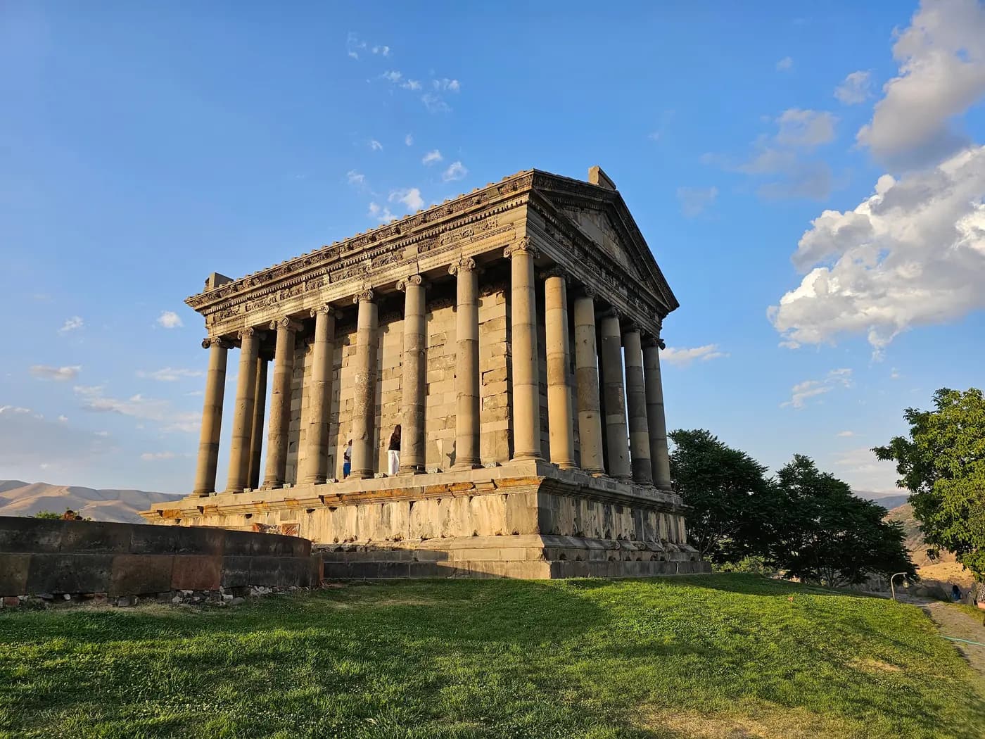The colonnade of Garni temple in low golden light with the gorge behind