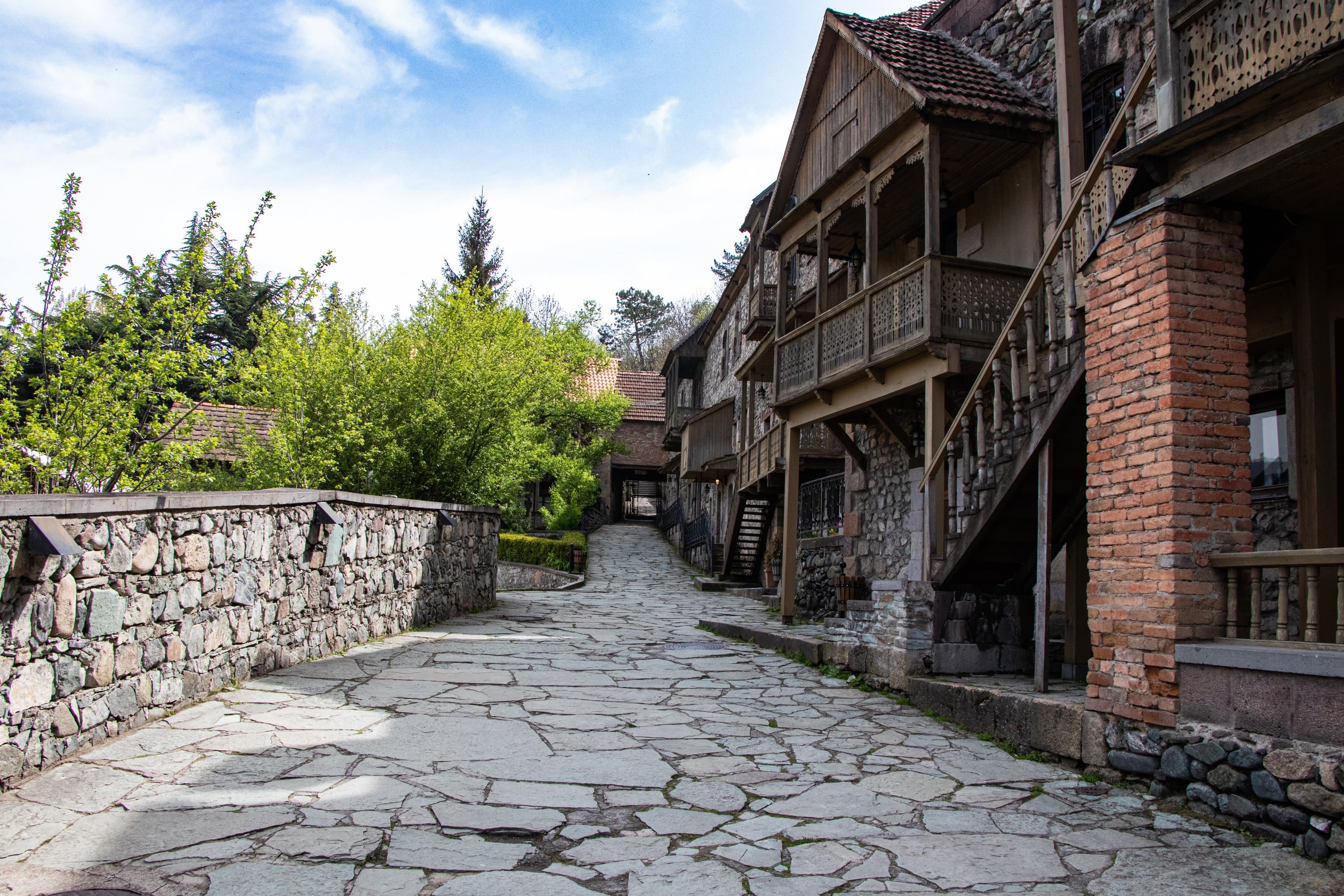 Sharambeyan Street in Dilijan: flagstone paving, a low stone wall, and houses with carved wooden balconies
