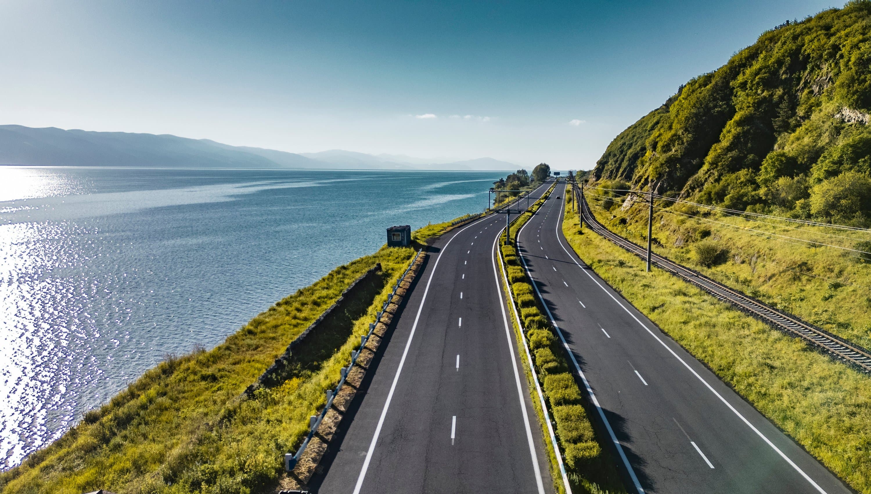 The road north of the pass running down beside Lake Sevan, green slopes on one side and the open water on the other