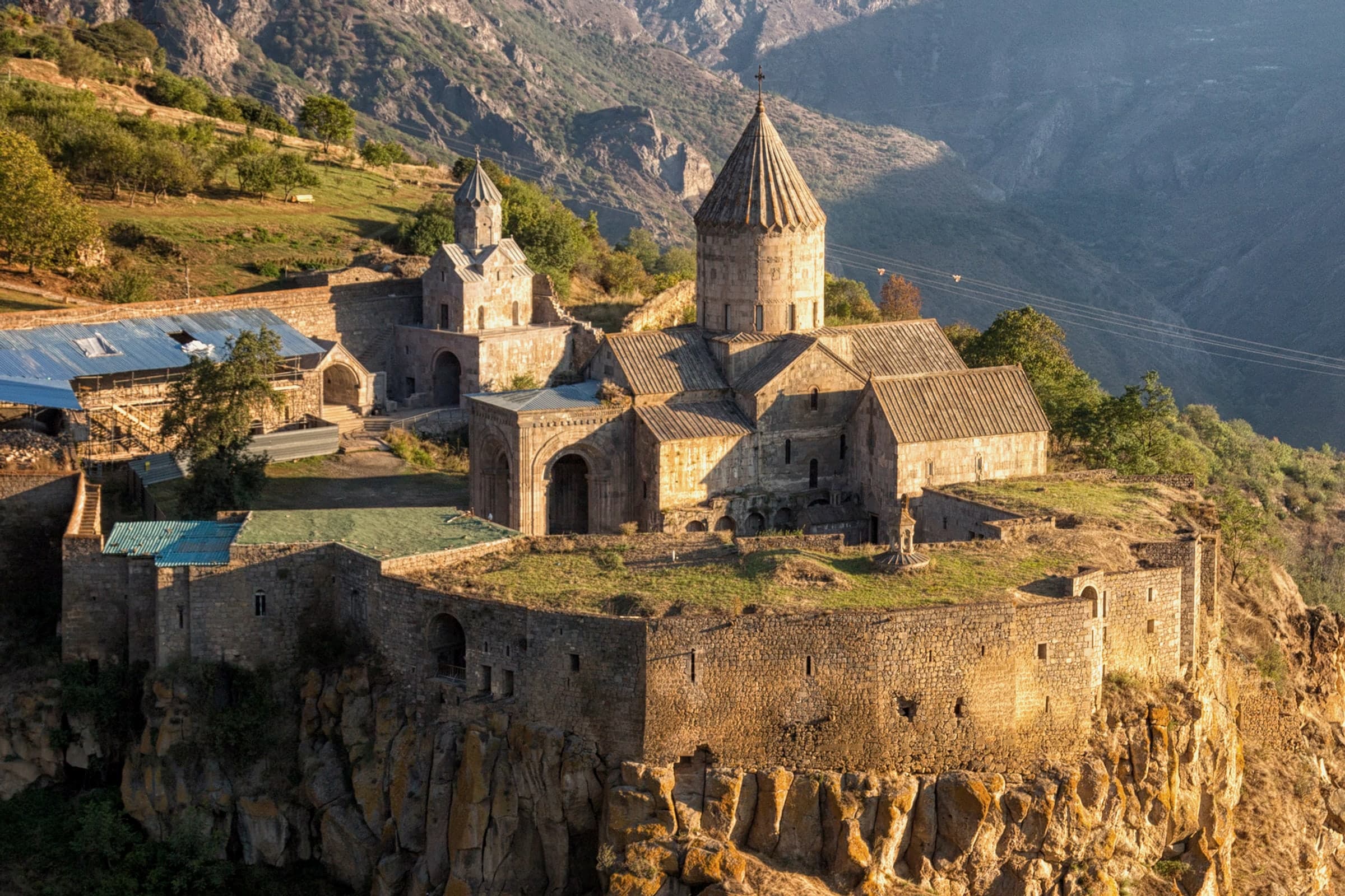 Tatev's walls and conical church drums, close, on the edge of its rock promontory